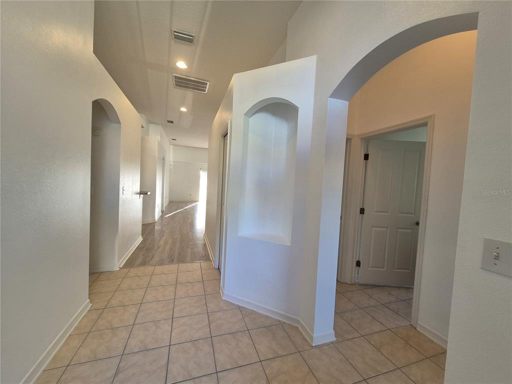 A tiled entryway leads to a hallway with wood-look flooring and an arched doorway — 6833 RUNNER OAK DRIVE, ZEPHYRHILLS, FL