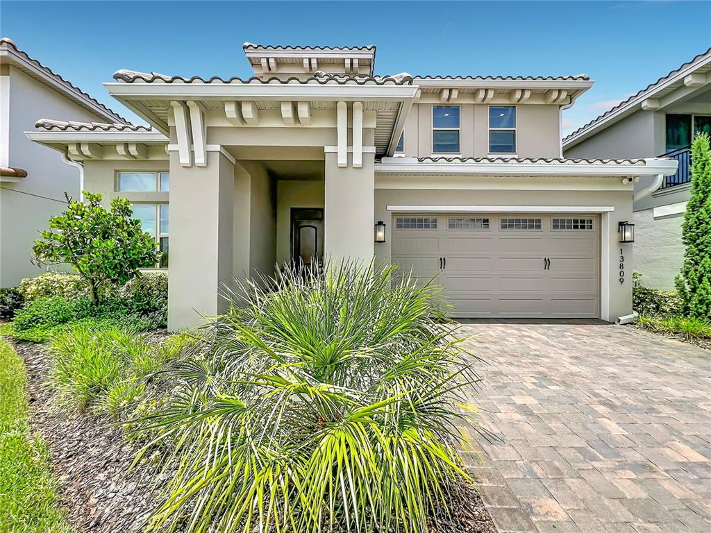 A two-story house with a beige stucco exterior, a tiled roof, and a paved driveway — 13809 LARKTON LANE, ORLANDO, FL