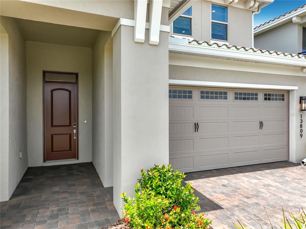 A beige house exterior features a brown front door, a garage, and a paved driveway — 13809 LARKTON LANE, ORLANDO, FL