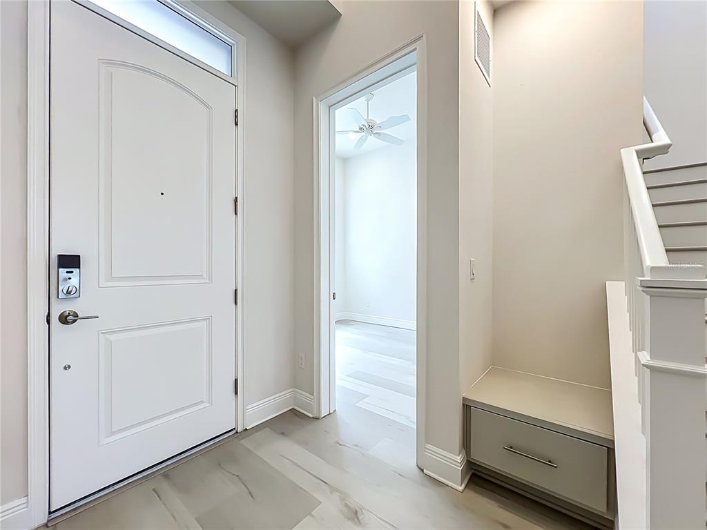 An entryway features a white front door, a built-in storage bench, and a staircase — 13809 LARKTON LANE, ORLANDO, FL