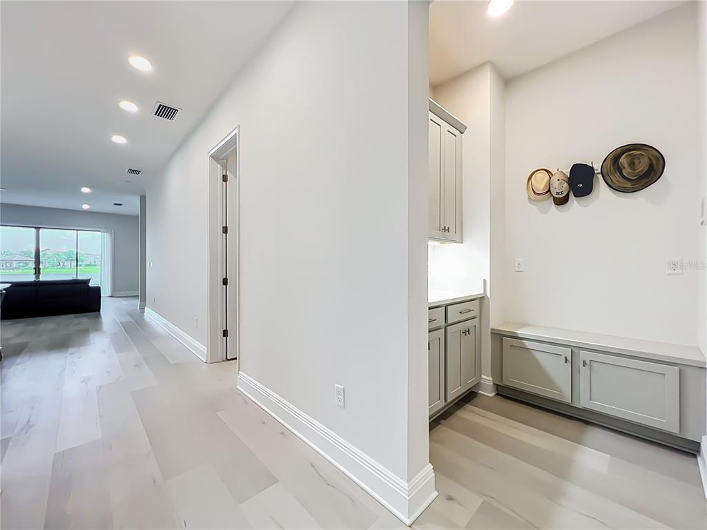 A hallway features light wood flooring, a built-in mudroom bench with cabinets, and a doorway — 13809 LARKTON LANE, ORLANDO, FL