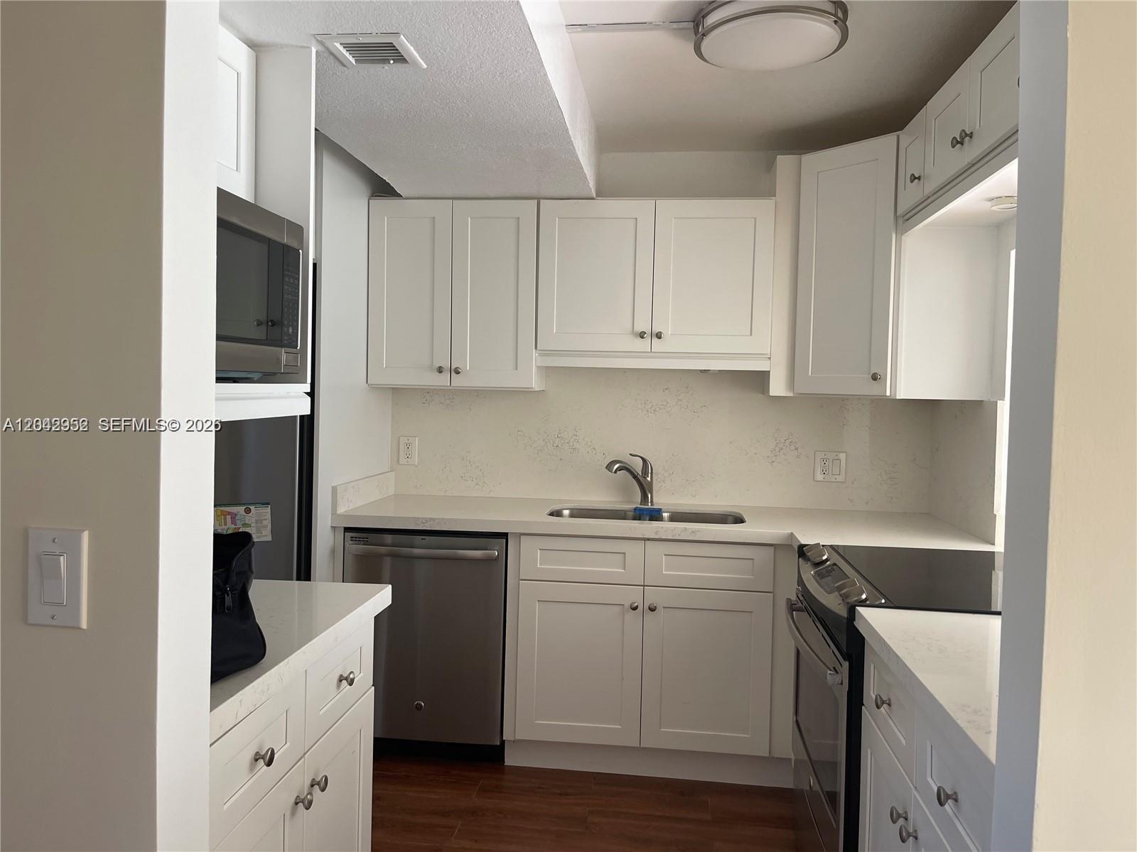 A kitchen features white cabinets, stainless steel appliances, and light-colored countertops — 9401 Evergreen Pl # 103, Davie FL 33324, DAVIE, FL
