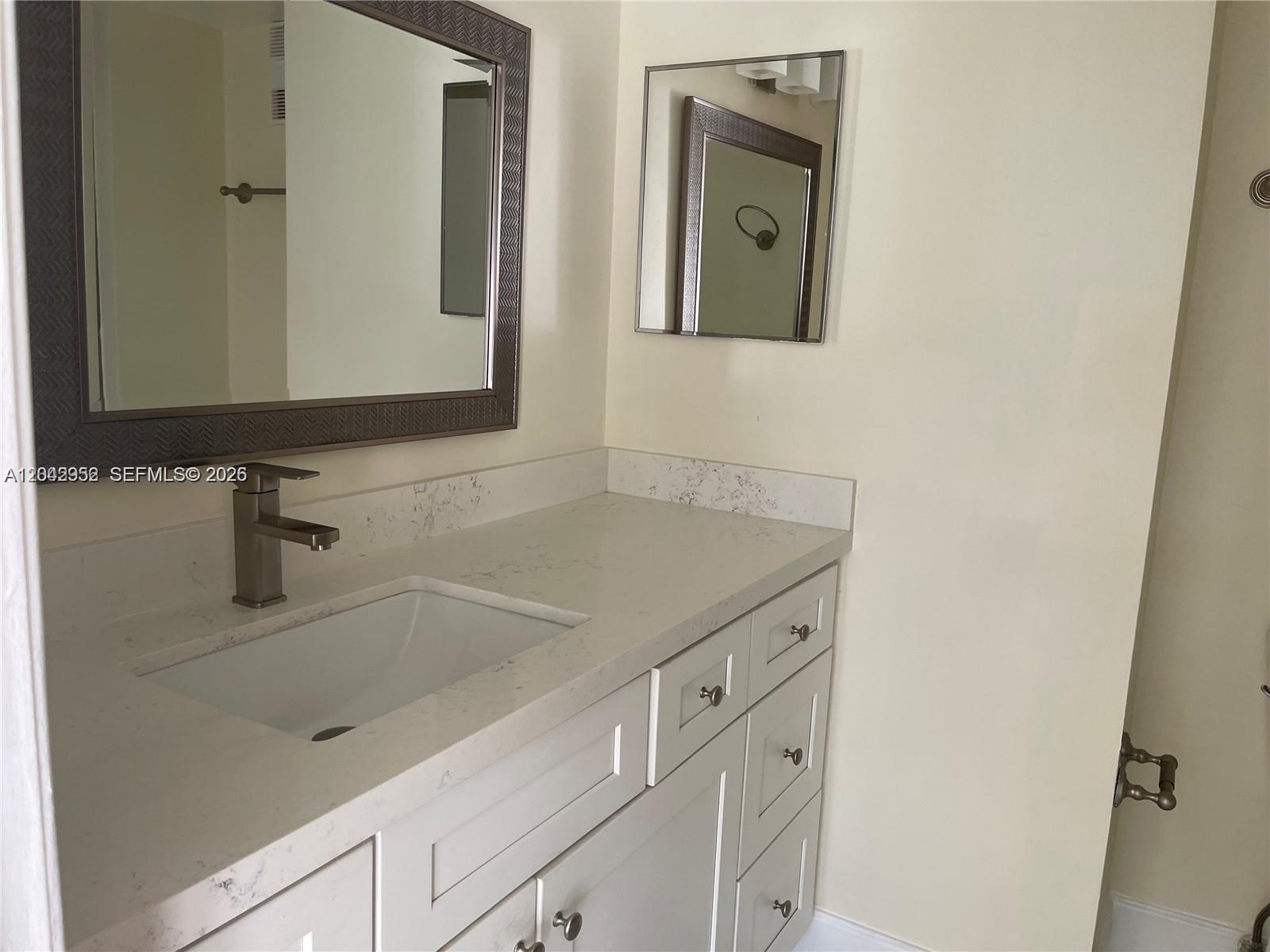 A bathroom vanity features a white countertop, a single sink, and a framed mirror — 9401 Evergreen Pl # 103, Davie FL 33324, DAVIE, FL