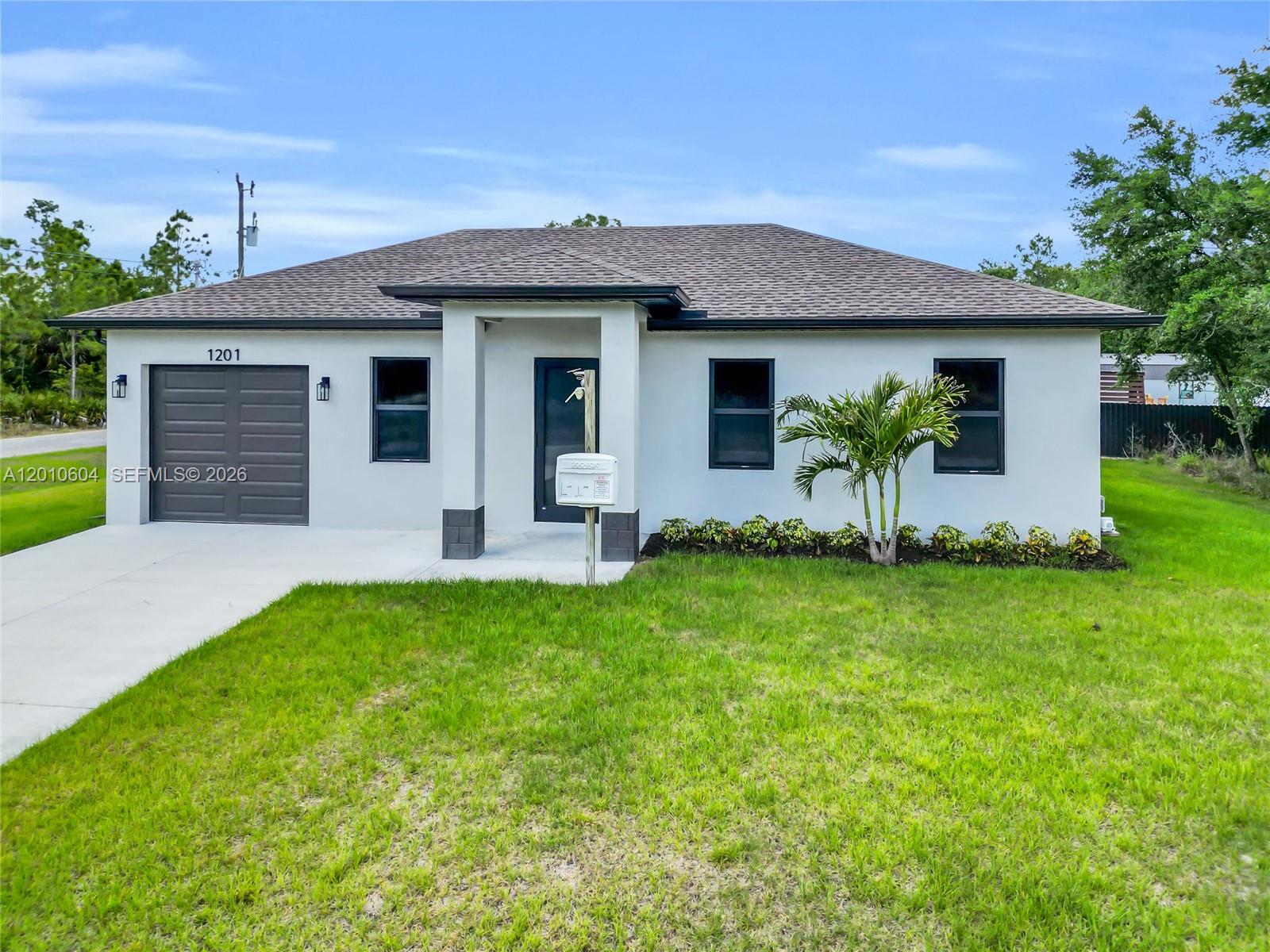 A single-story house with a gray garage, white stucco exterior, and a dark shingled roof — 1201 E 7th ST, Lehigh Acres FL 33972, LEHIGH ACRES, FL