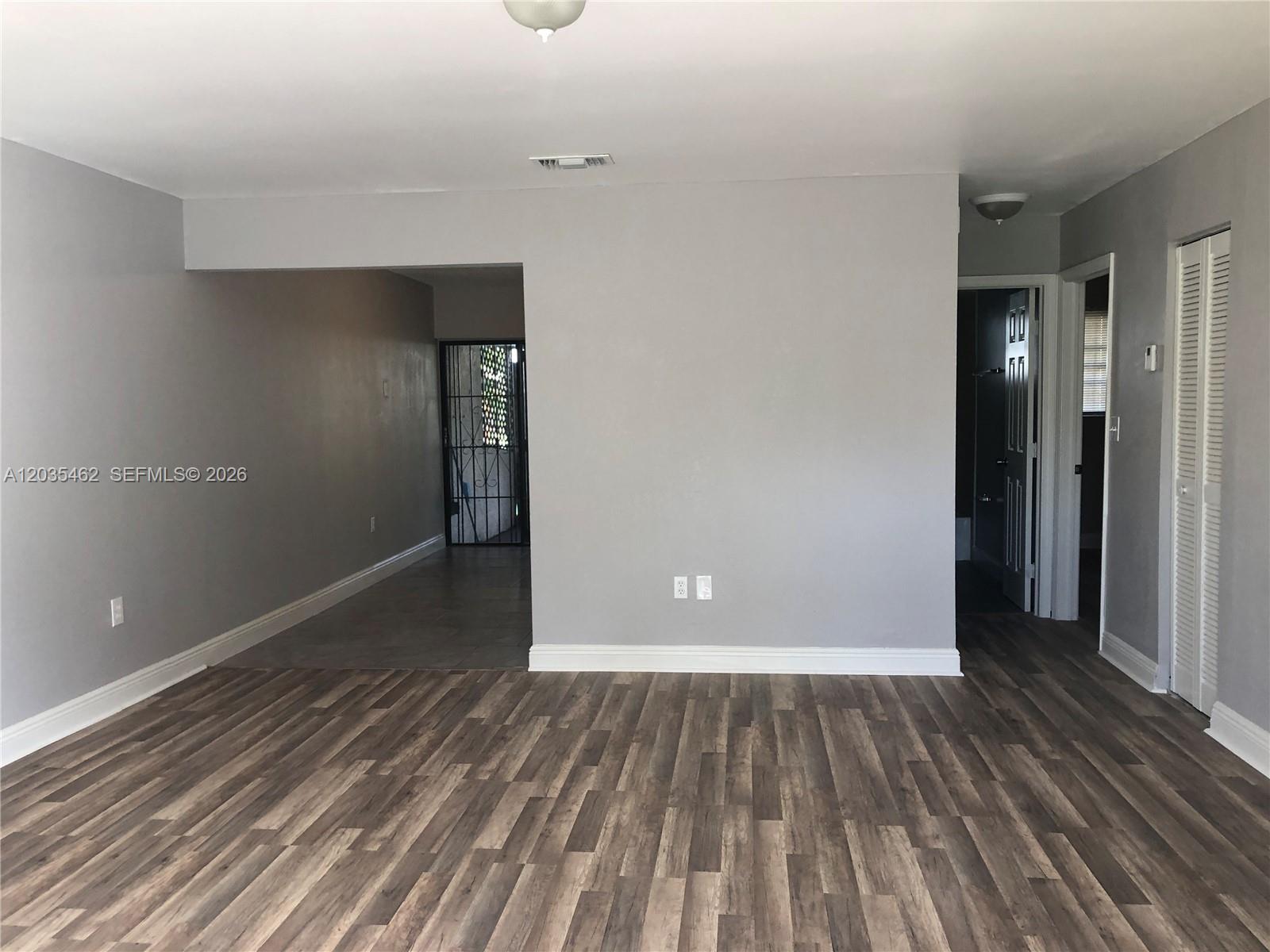 An empty room features gray walls, wood-look flooring, and a doorway leading to a tiled area — 13963 NE 3rd Ct # D2, North Miami FL 33161, NORTH MIAMI, FL