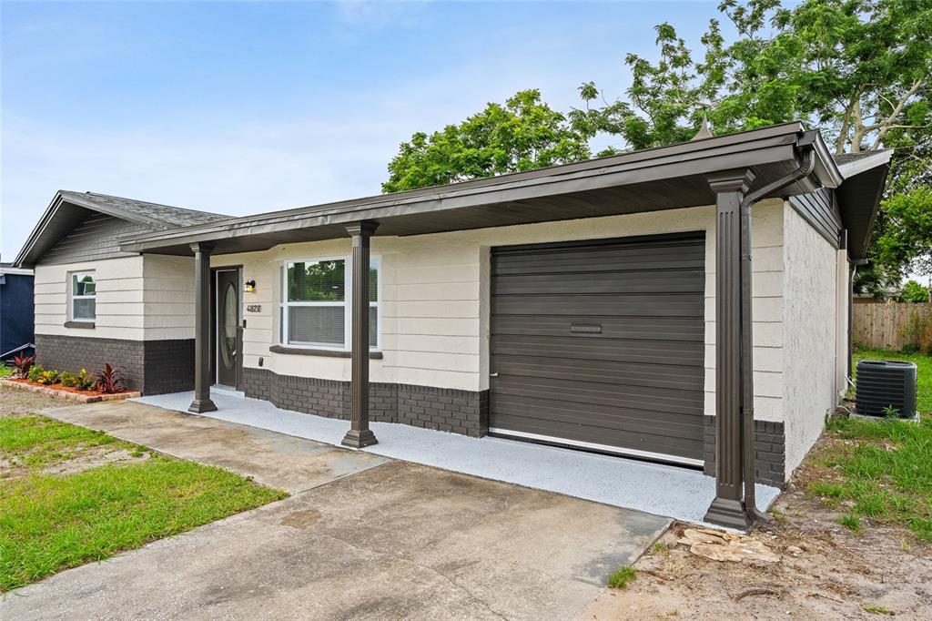 A single-story house features a cream-colored stucco exterior, dark brick accents, and a covered carport — 4820 SALEM DRIVE, NEW PORT RICHEY, FL