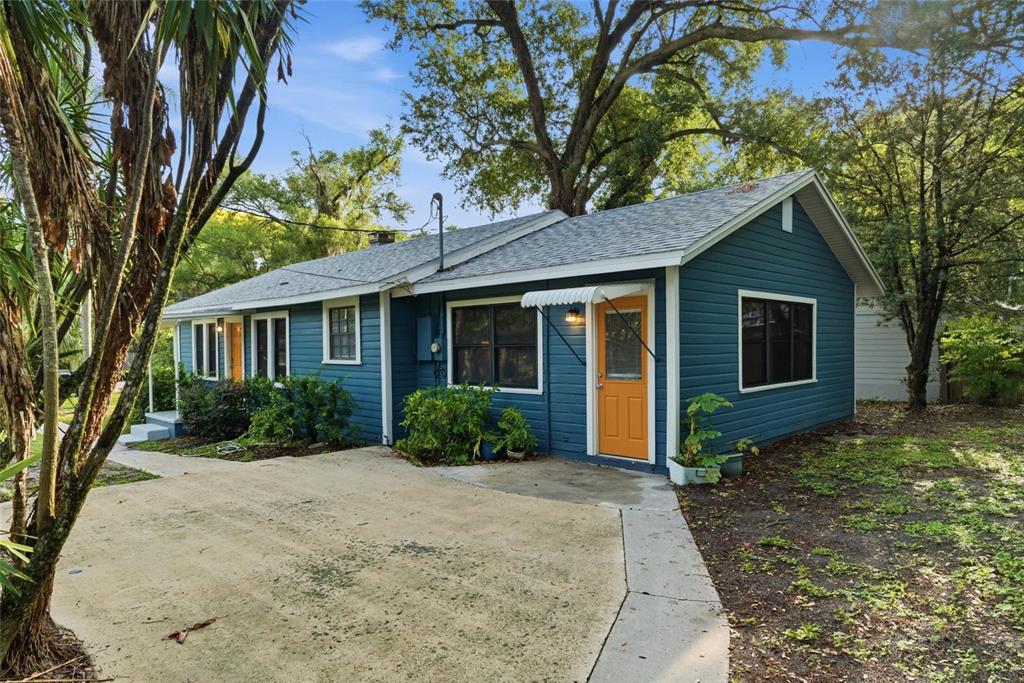 A blue-sided house with an orange door and a concrete driveway under large trees — 2206 PAGE AVENUE, ORLANDO, FL
