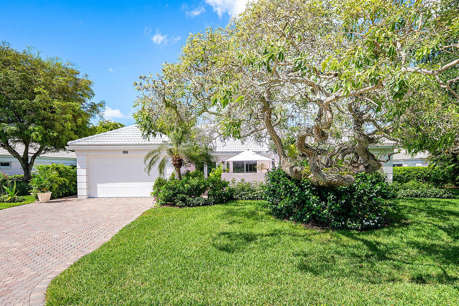 A single-story house with a white garage and a large, gnarled tree in the yard — 4419 E Sanderling Cir, Boynton Beach FL 33436, BOYNTON BEACH, FL