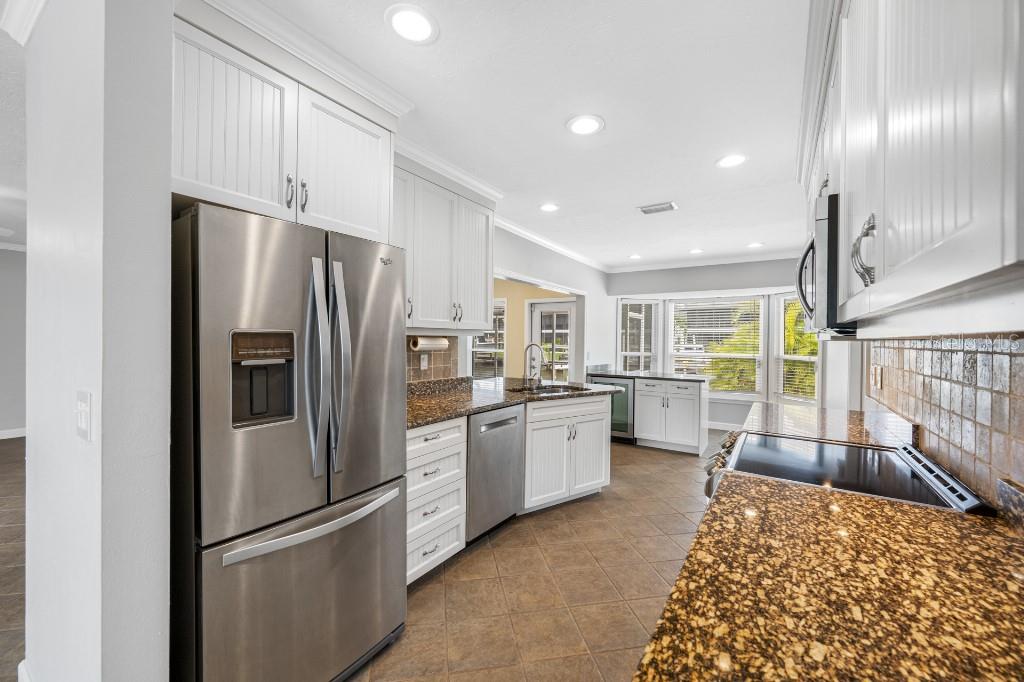 A kitchen with white cabinets, stainless steel appliances, granite countertops, and tile flooring — 10308 SANDPIPER ROAD W, BRADENTON, FL