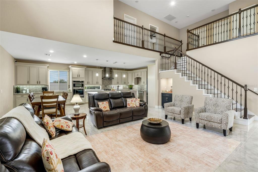 An open-concept living room and kitchen feature a staircase, tile floors, and neutral cabinetry — 545 GANDHI DRIVE, LAKELAND, FL