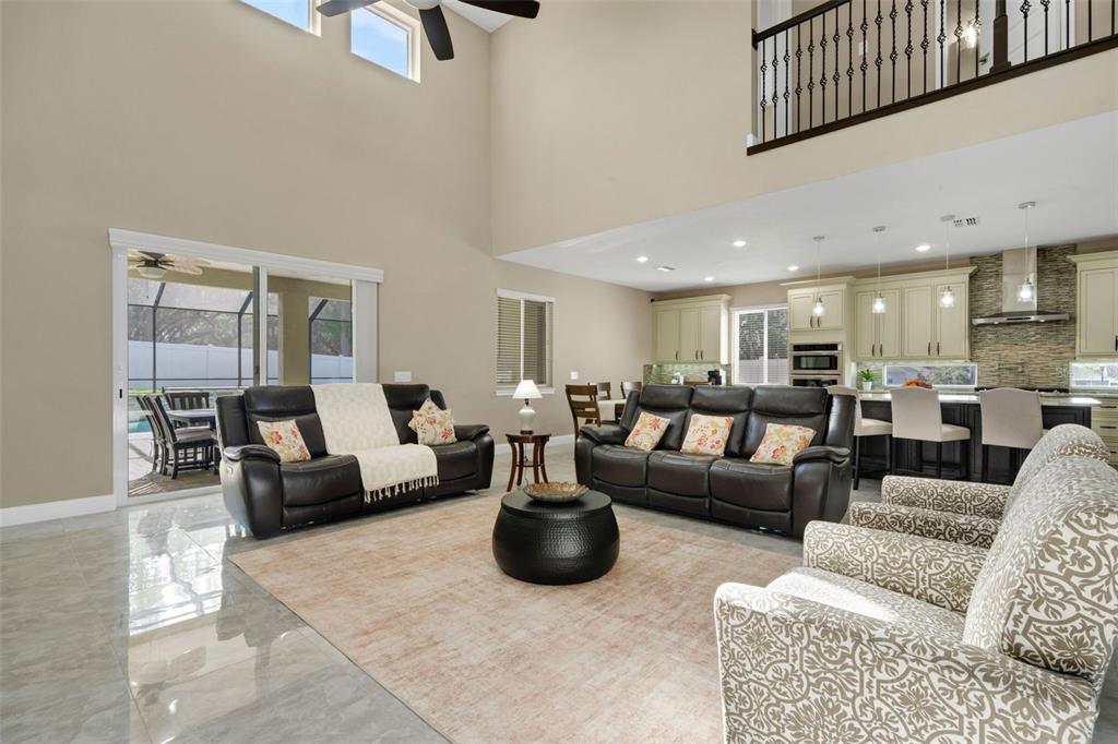A spacious living room with high ceilings, tile floors, and an open-concept kitchen — 545 GANDHI DRIVE, LAKELAND, FL