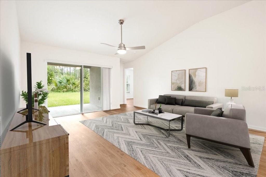 A living room features a gray sofa, a patterned rug, and a sliding glass door — 192 PERSIMMON DRIVE, PALM COAST, FL