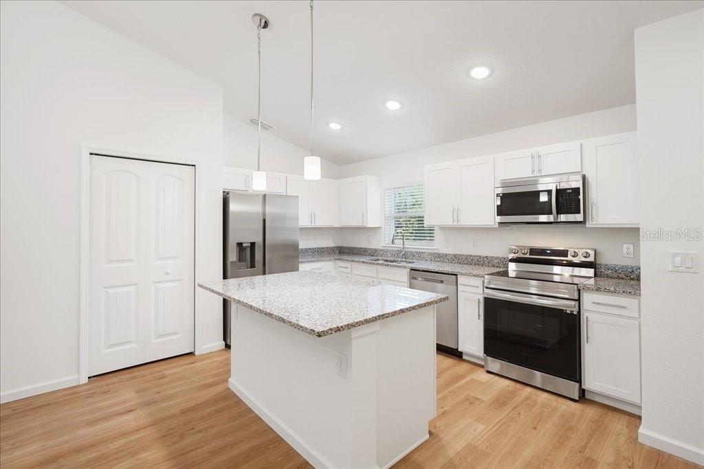 A kitchen features white cabinets, granite countertops, stainless steel appliances, and a central island — 192 PERSIMMON DRIVE, PALM COAST, FL