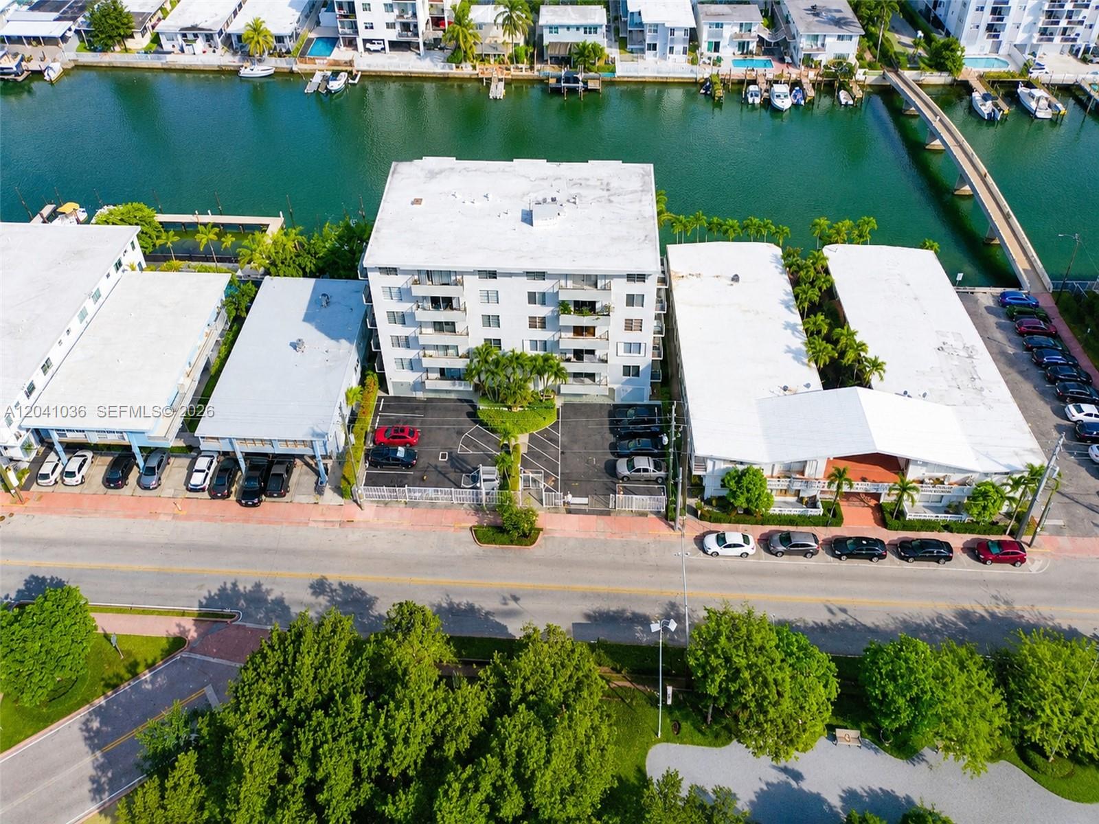 An aerial view shows a multi-story apartment building with a parking lot beside a canal — 8024 Tatum Waterway Dr # 2B, Miami Beach FL 33141, MIAMI BEACH, FL