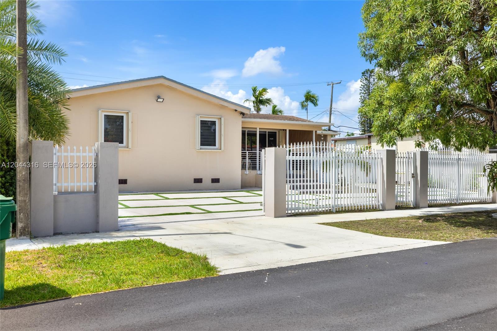 A single-story beige house features a white metal fence and a paved driveway — 8330 SW 25th St, Miami FL 33155, MIAMI, FL