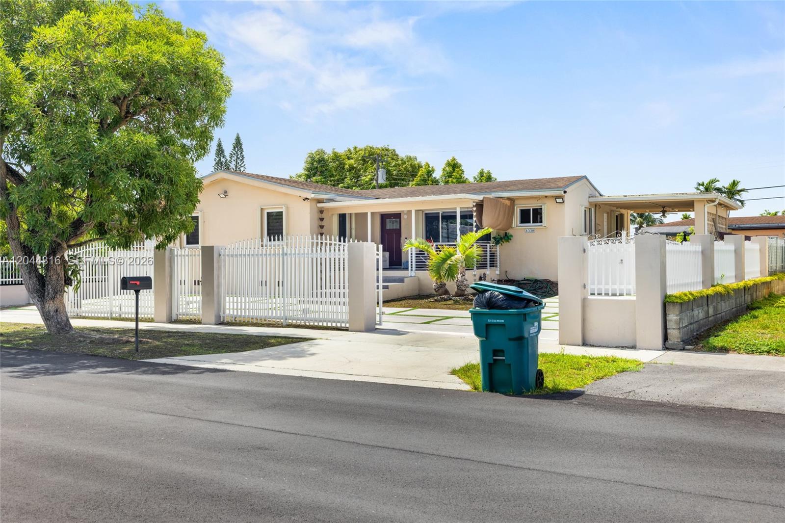 A single-story house features a white fence, a paved driveway, and a large shade tree — 8330 SW 25th St, Miami FL 33155, MIAMI, FL