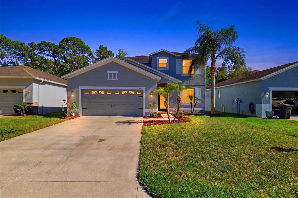 A two-story suburban house with a gray exterior, a two-car garage, and a palm tree — 12832 SAULSTON PLACE, HUDSON, FL