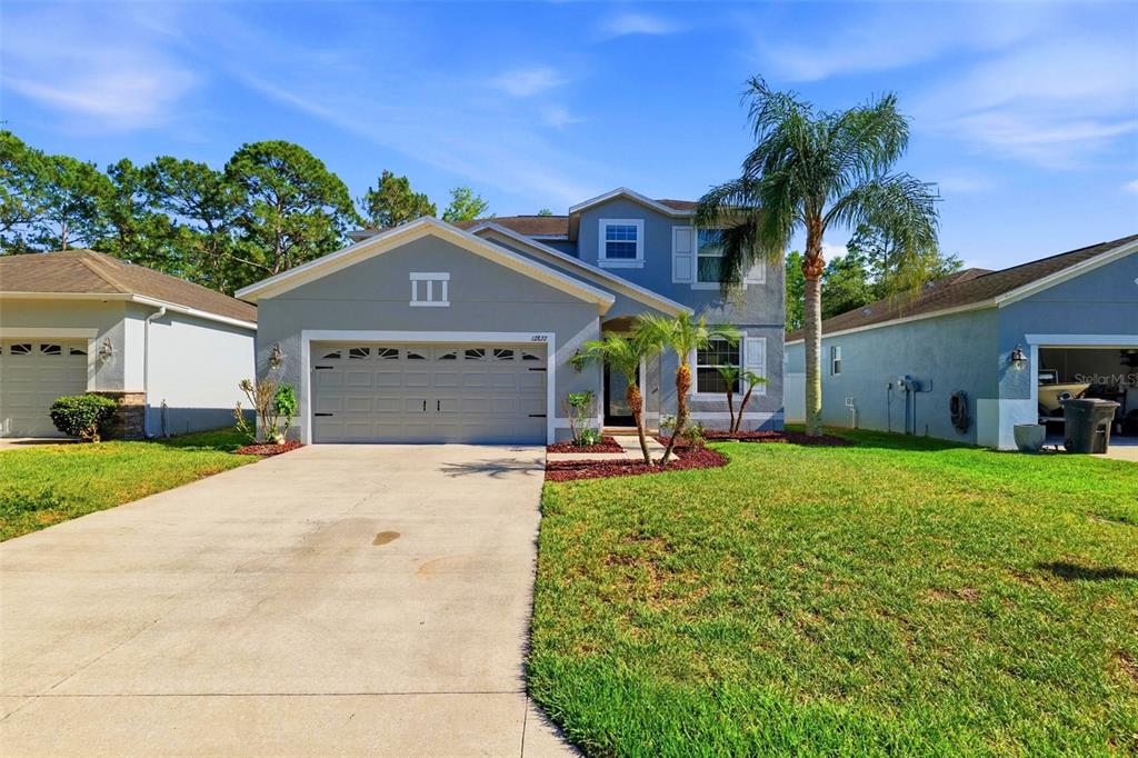A two-story suburban house with a gray exterior, a two-car garage, and a palm tree — 12832 SAULSTON PLACE, HUDSON, FL