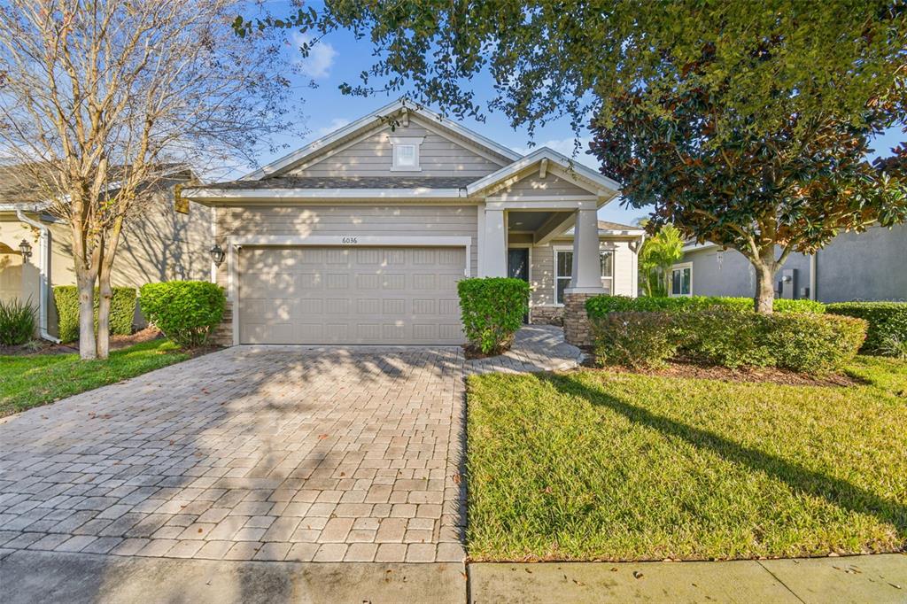 A single-story house with a beige exterior, stone accents, and a paved driveway — 6036 PLOVER MEADOW STREET, LITHIA, FL