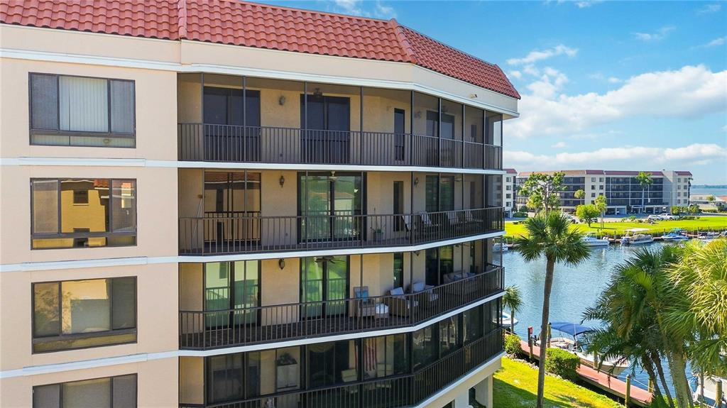 An exterior view of a multi-story apartment building with screened balconies overlooking a canal — 25188 MARION AVENUE UNIT D308, PUNTA GORDA, FL