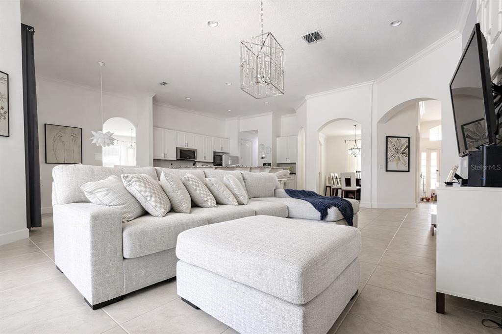 A bright living room features a large gray sectional sofa, a matching ottoman, and tile flooring — 4084 OAKTREE DRIVE, DAVENPORT, FL