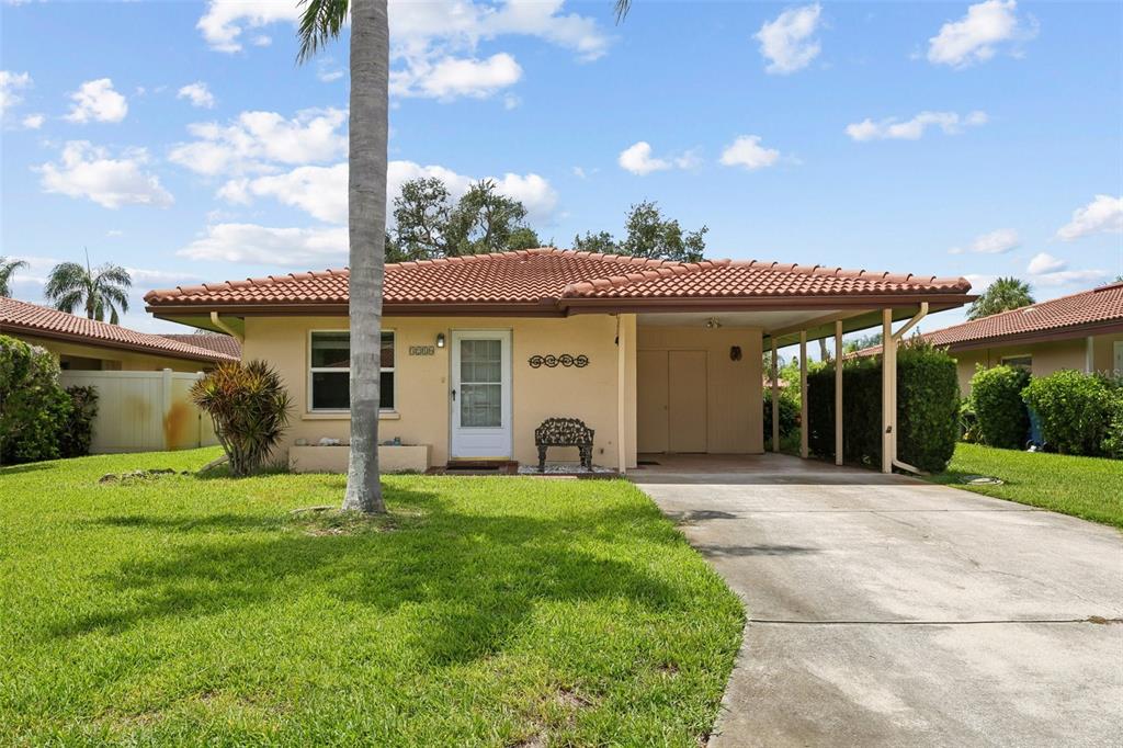 A single-story house with a terracotta tile roof, a carport, and a front lawn — 3210 CAMBRIDGE AVENUE, BRADENTON, FL