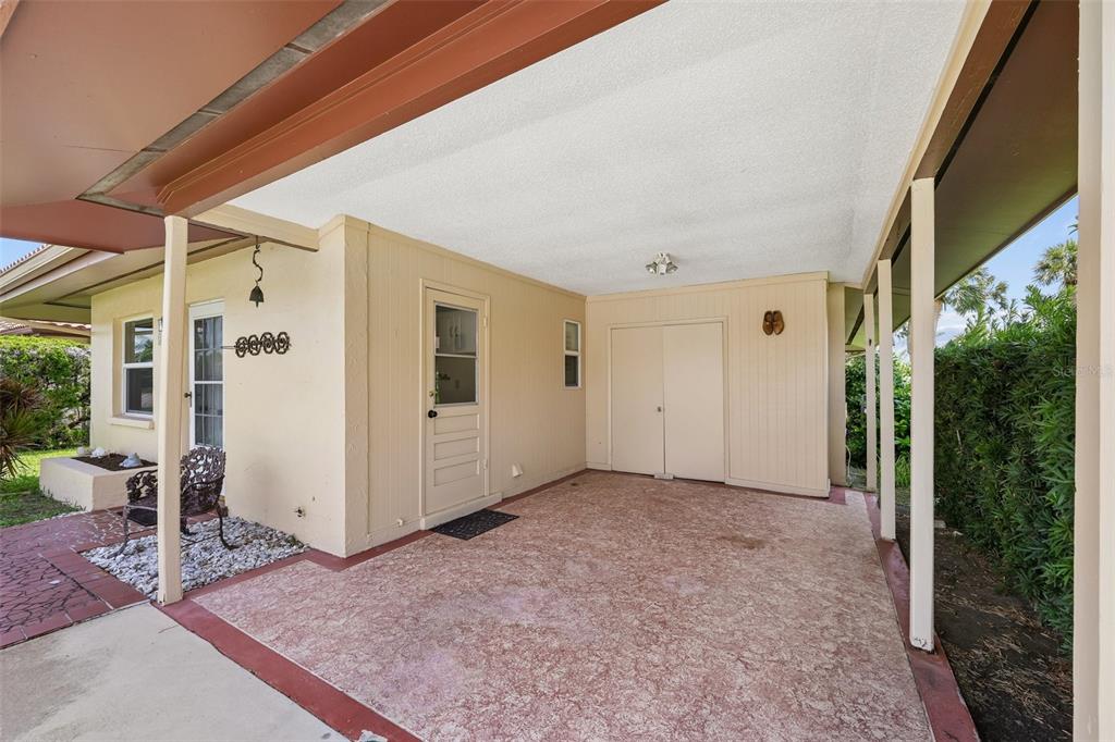 A covered carport with a concrete floor, a storage closet, and a side entry door — 3210 CAMBRIDGE AVENUE, BRADENTON, FL
