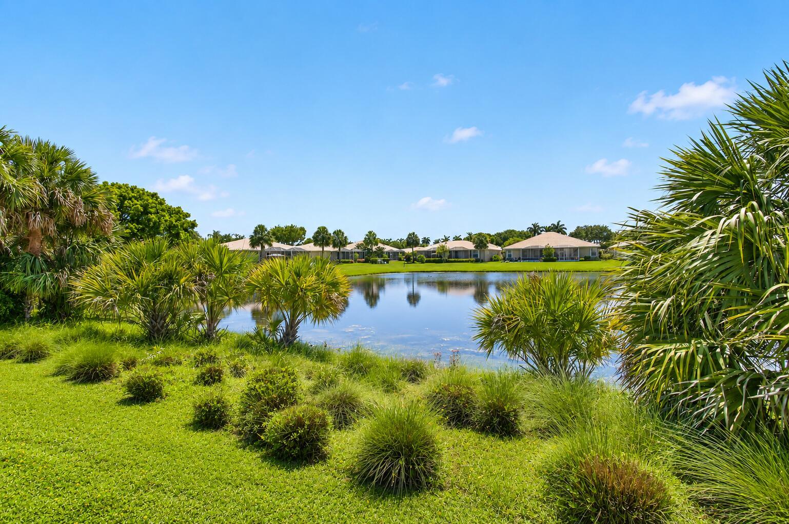 A pond sits in front of residential buildings surrounded by palm trees and green grass — 10773 Royal Caribbean Circle, Boynton Beach FL 33437, BOYNTON BEACH, FL