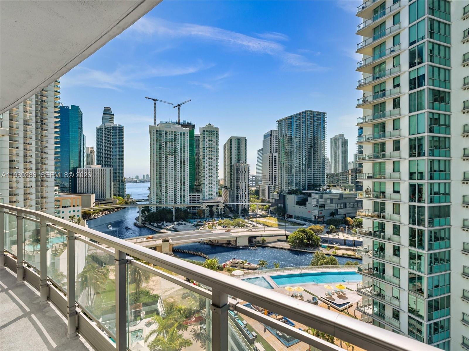 A high-rise balcony overlooks a river, city skyline, and a swimming pool deck — 90 SW 3rd St # 2013, Miami FL 33130, MIAMI, FL