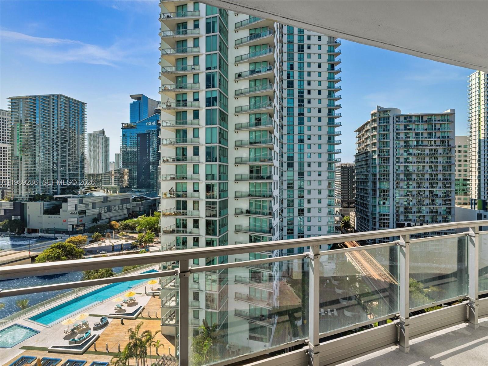 A balcony view overlooks a swimming pool and surrounding high-rise apartment buildings in a city — 90 SW 3rd St # 2013, Miami FL 33130, MIAMI, FL