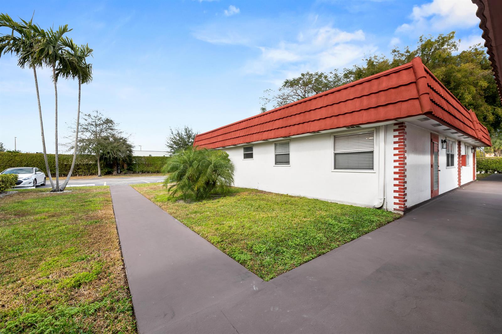 A white single-story building with a red mansard roof sits beside a paved walkway — 4 Seville Terrace # 4, Delray Beach FL 33446, DELRAY BEACH, FL