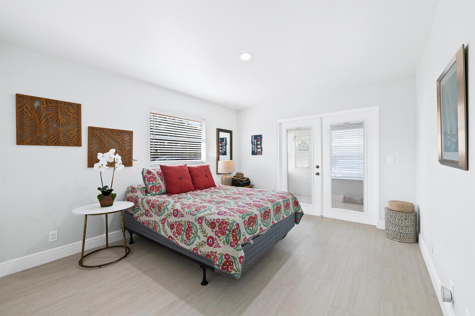 A bedroom with light wood-look tile floors, a floral bedspread, and glass patio doors — 4 Seville Terrace # 4, Delray Beach FL 33446, DELRAY BEACH, FL