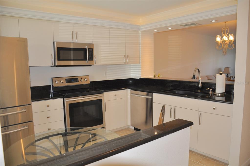 A kitchen with white cabinets, stainless steel appliances, and black granite countertops — 4000 BAL HARBOR BOULEVARD UNIT 214, PUNTA GORDA, FL
