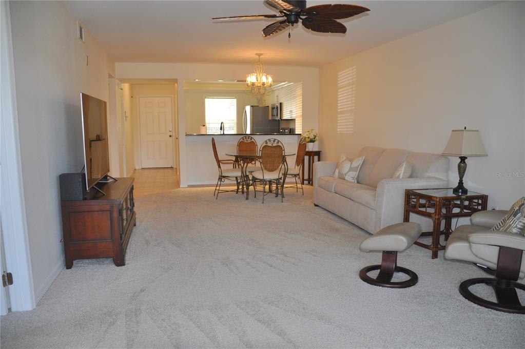 A living room with beige carpet, a sofa, a dining set, and a ceiling fan — 4000 BAL HARBOR BOULEVARD UNIT 214, PUNTA GORDA, FL