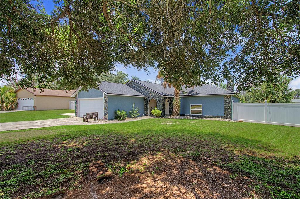 A blue single-story house with a stone facade, a garage, and a large front lawn — 14390 SW 46TH COURT, OCALA, FL