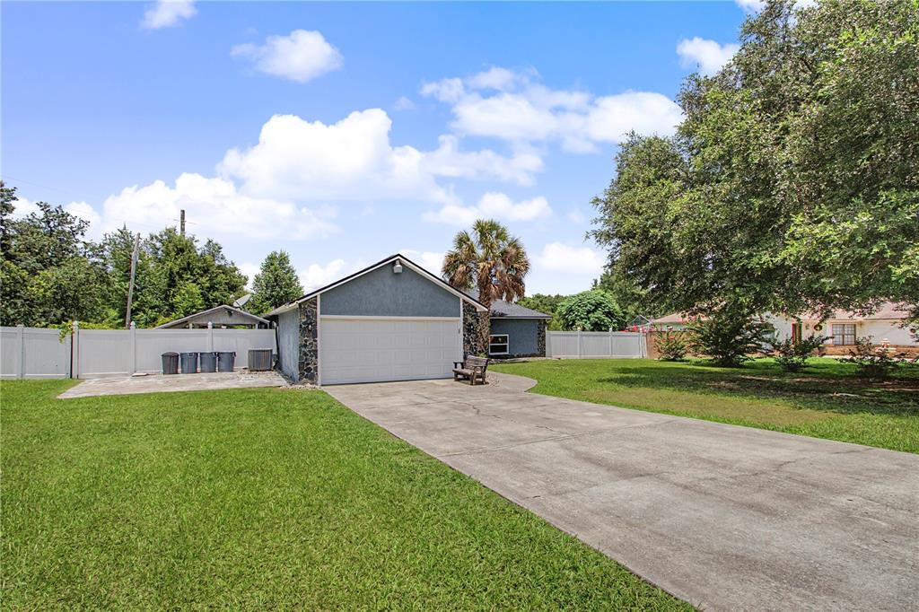 A detached garage with a concrete driveway and a white fence in a grassy yard — 14390 SW 46TH COURT, OCALA, FL