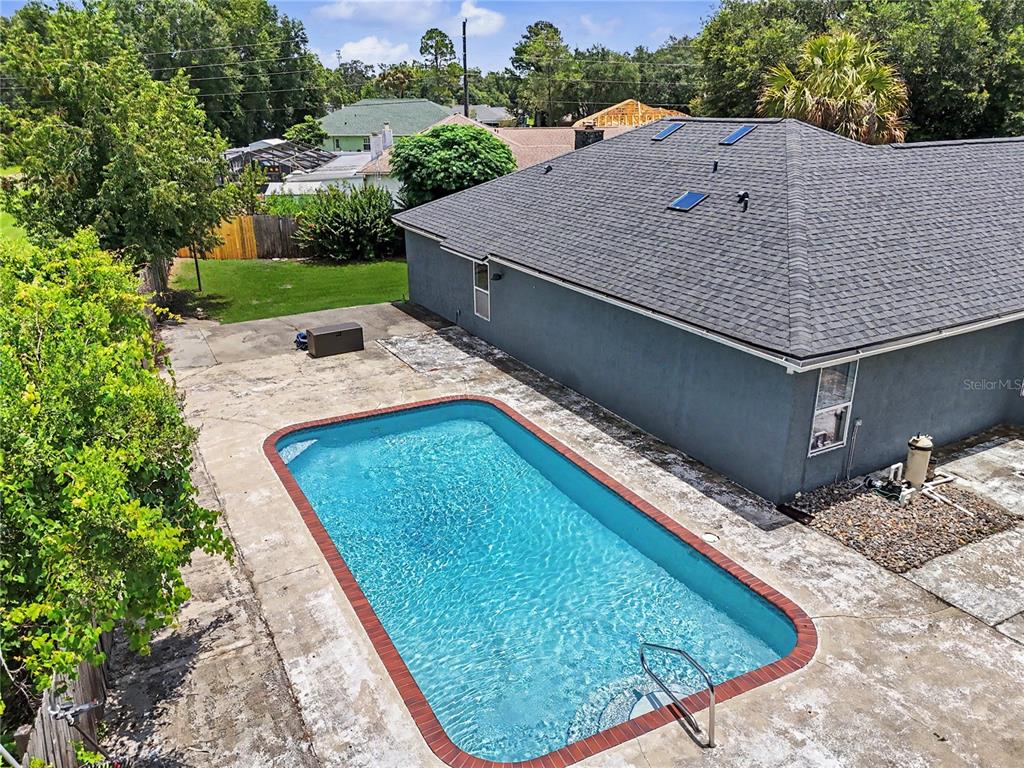 An aerial view of a backyard featuring a rectangular swimming pool and a gray house — 14390 SW 46TH COURT, OCALA, FL