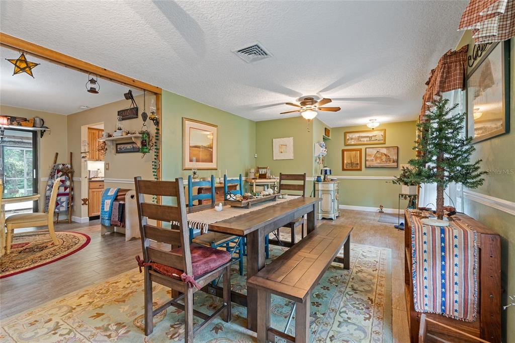 A dining room features a wooden table with chairs and a bench on a patterned rug — 155 WOODCUTTER LANE, PALM HARBOR, FL