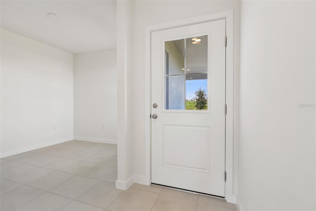 A white door with a glass pane opens into a room with light-colored tile flooring — 1976 DIAMOND HEAD CIRCLE, HAINES CITY, FL