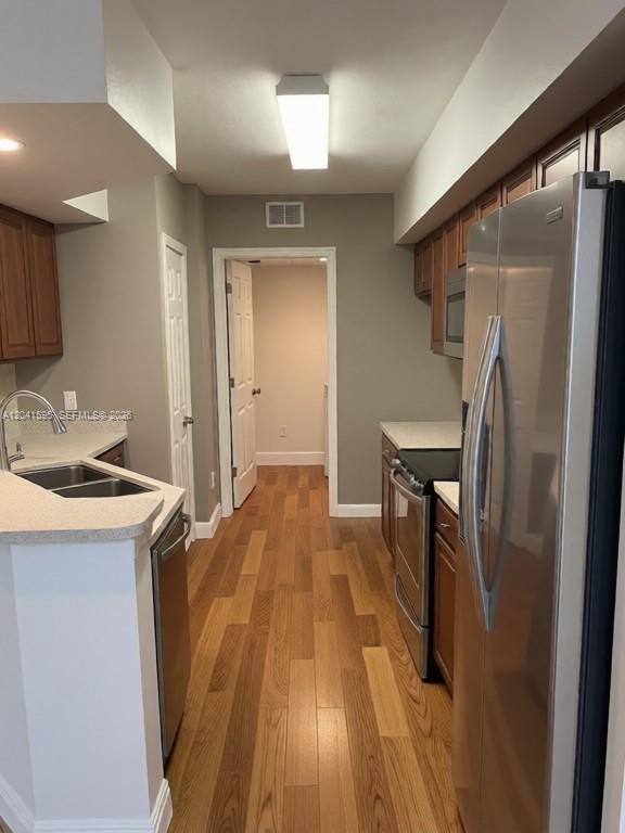 A kitchen features wood cabinets, stainless steel appliances, light countertops, and wood-look flooring — 738 Crest Pines Dr # 0, Orlando FL 32828, ORLANDO, FL