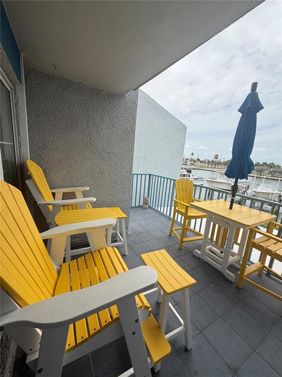 A balcony with yellow and white patio furniture overlooks a marina with boats — 315 MEDALLION BOULEVARD UNIT H, MADEIRA BEACH, FL
