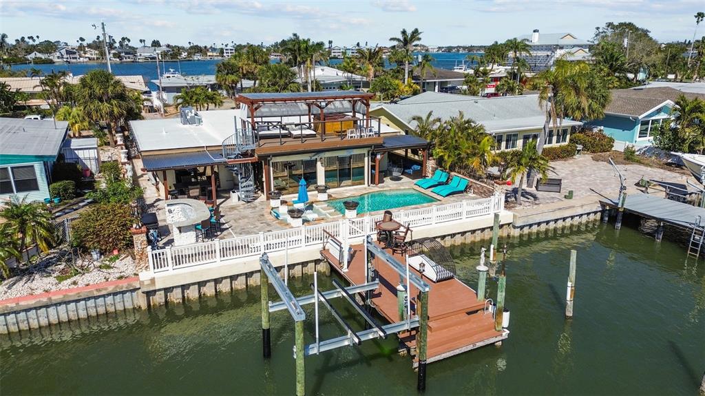 An aerial view of a waterfront house with a pool, deck, and private boat lift — 357 LA HACIENDA DRIVE, INDIAN ROCKS BEACH, FL