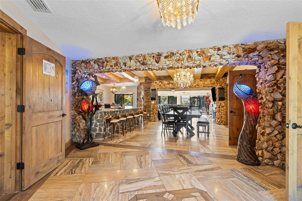 A room with stone-clad archways, tile flooring, and two decorative peacock-shaped floor lamps — 357 LA HACIENDA DRIVE, INDIAN ROCKS BEACH, FL