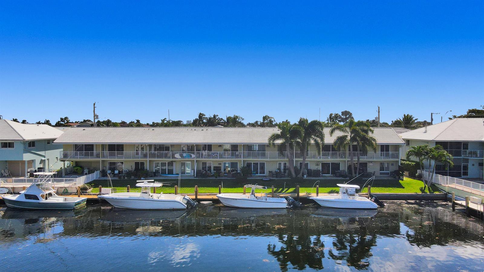 An exterior view of a multi-story apartment building with a canal and docked boats — 2311 NE 36th Street # 2f, Lighthouse Point FL 33064, LIGHTHOUSE POINT, FL