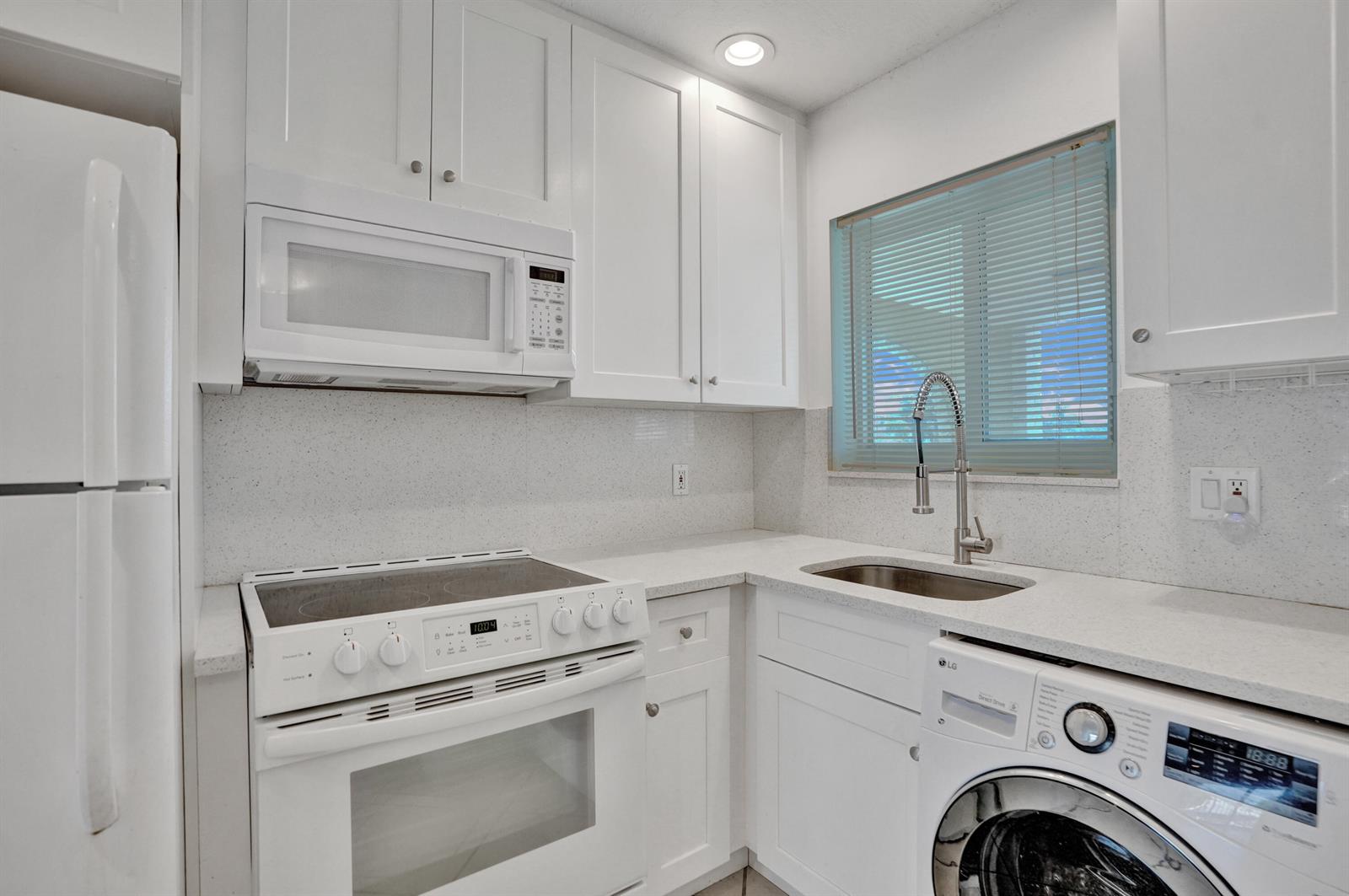 A small white kitchen features a refrigerator, stove, sink, and a built-in washing machine — 2311 NE 36th Street # 2f, Lighthouse Point FL 33064, LIGHTHOUSE POINT, FL