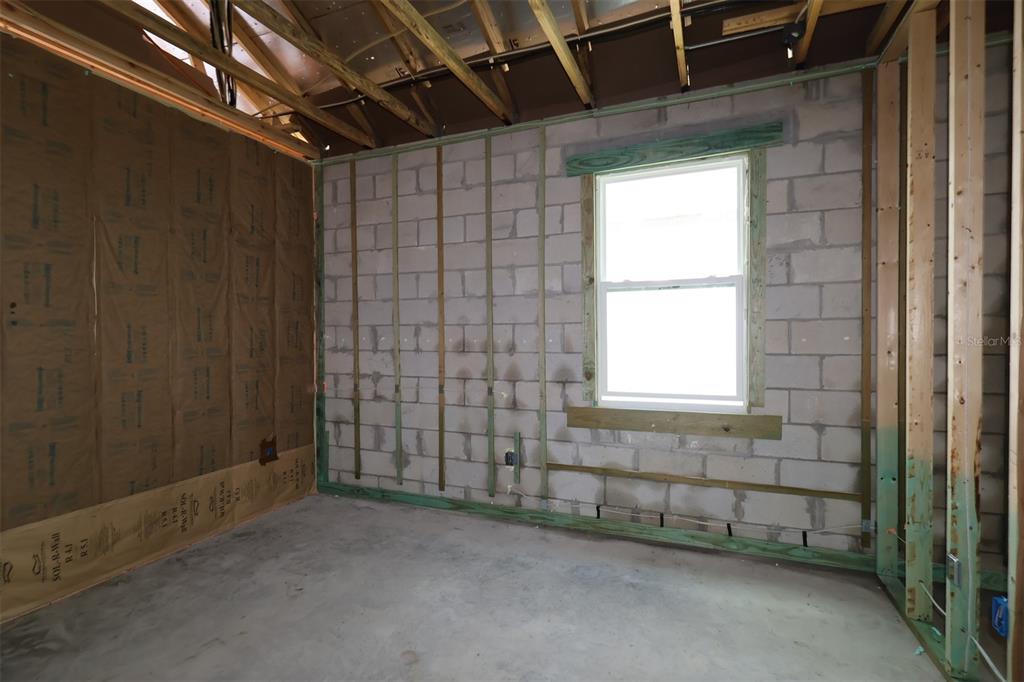 An unfinished room features concrete block walls, exposed wood framing, and a single window — 845 RIVER STONE TRAIL, SANFORD, FL