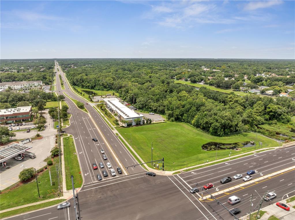 An aerial view shows a multi-lane intersection with a commercial building and adjacent vacant land — 3370 ROUSE ROAD UNIT 102, ORLANDO, FL