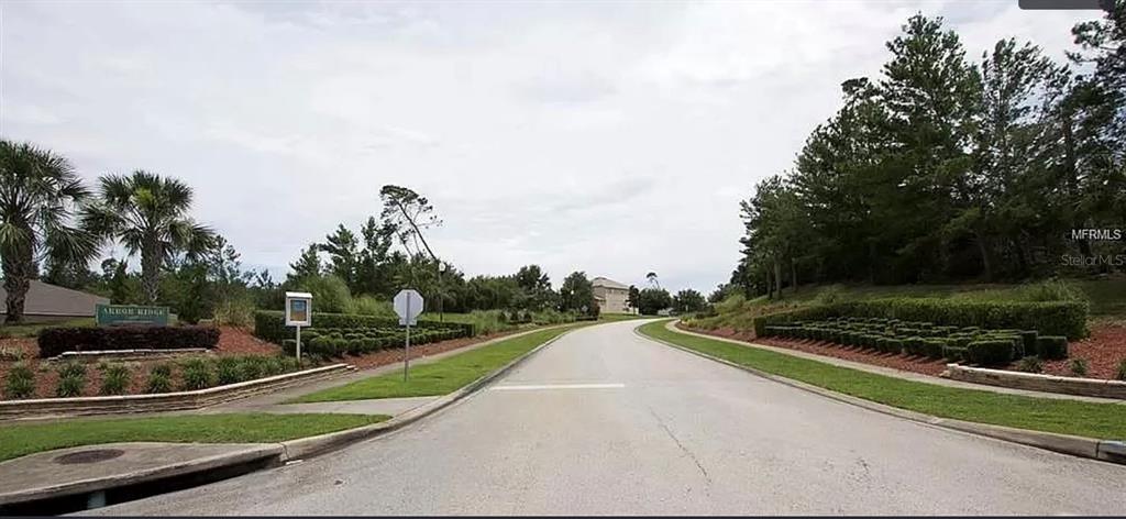 A paved road leads into a residential neighborhood with a landscaped entrance sign — 3260 SORREL COURT, DELTONA, FL