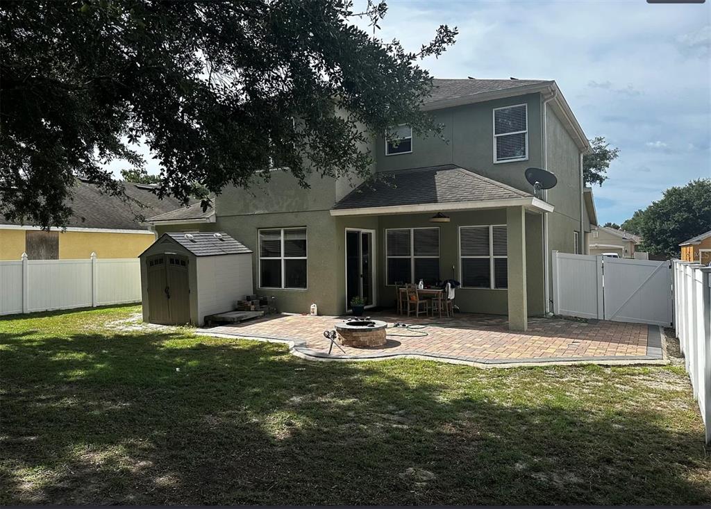The exterior rear view of a two-story house features a paved patio and storage shed — 3260 SORREL COURT, DELTONA, FL