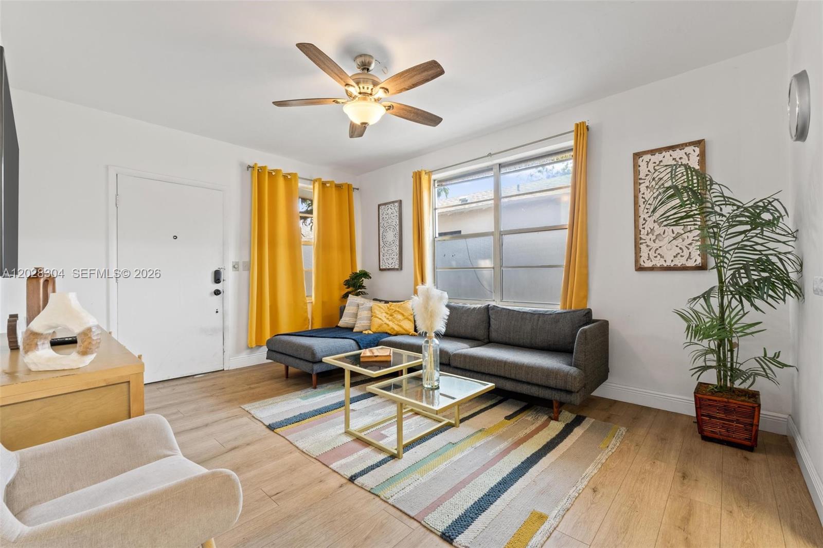 A living room features a gray sectional sofa, yellow curtains, and a glass coffee table — 2453 SW 17th St, Miami FL 33145, MIAMI, FL
